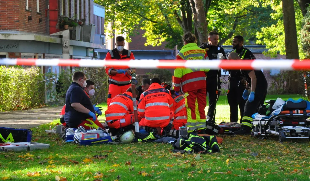 Rettungskräfte stehen auf einer Wiese um eine verletzte Person