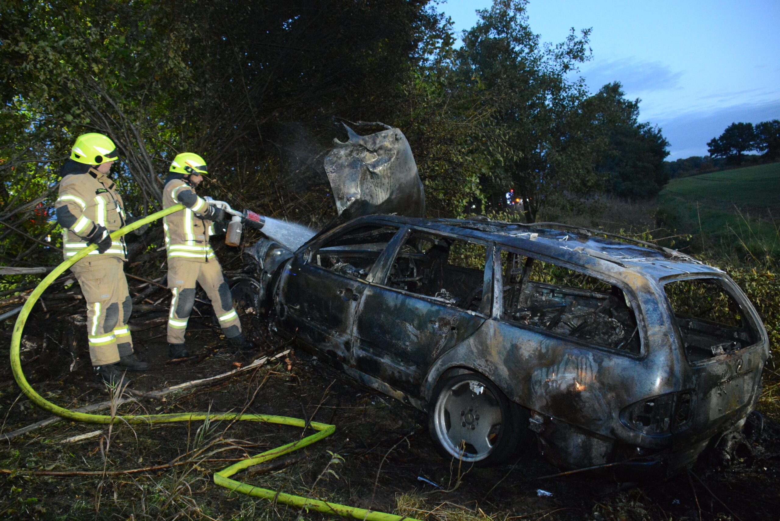 Feuerwehrmänner löschen den brennenden Mercedes. Der Fahrer soll alkoholisiert gewesen sein.