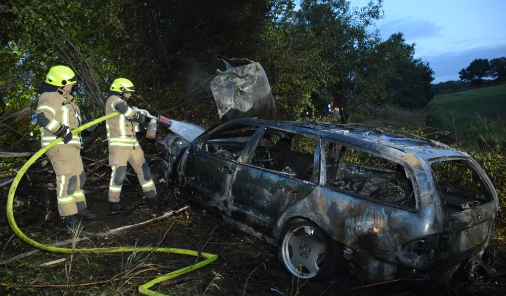 Feuerwehrmänner löschen den brennenden Mercedes. Der Fahrer soll alkoholisiert gewesen sein.