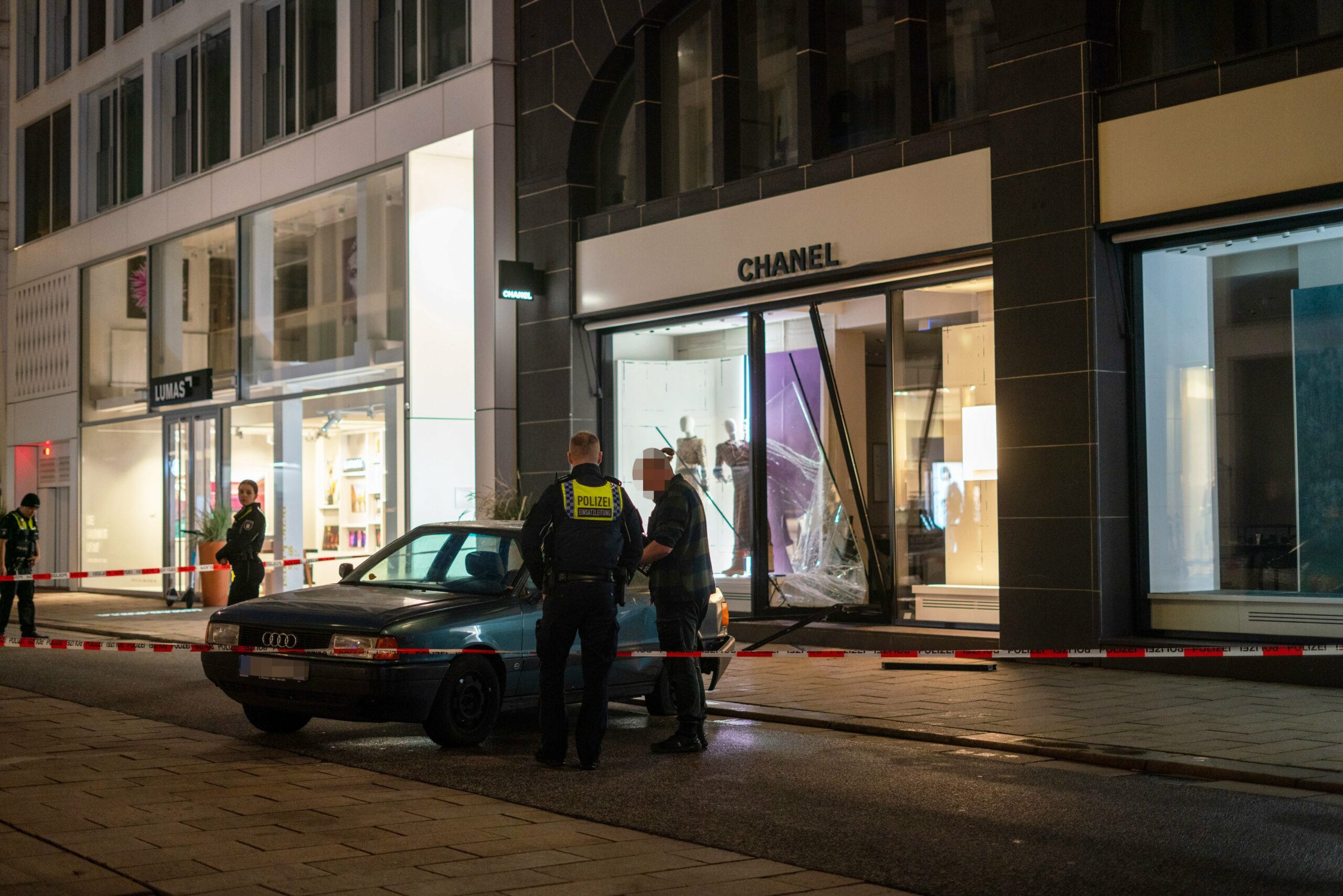Ein Audi 80 steht vor dem zerstörten Schaufenster von Chanel am Neuen Wall