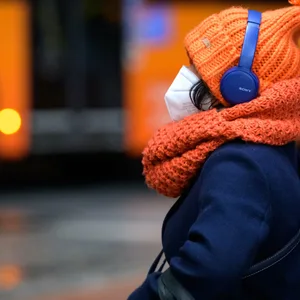 Frau wartet mit FFP2-Maske auf den Bus.