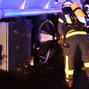 Feuerwehrmänner löschen den brennenden Reifen des Tankwagens.