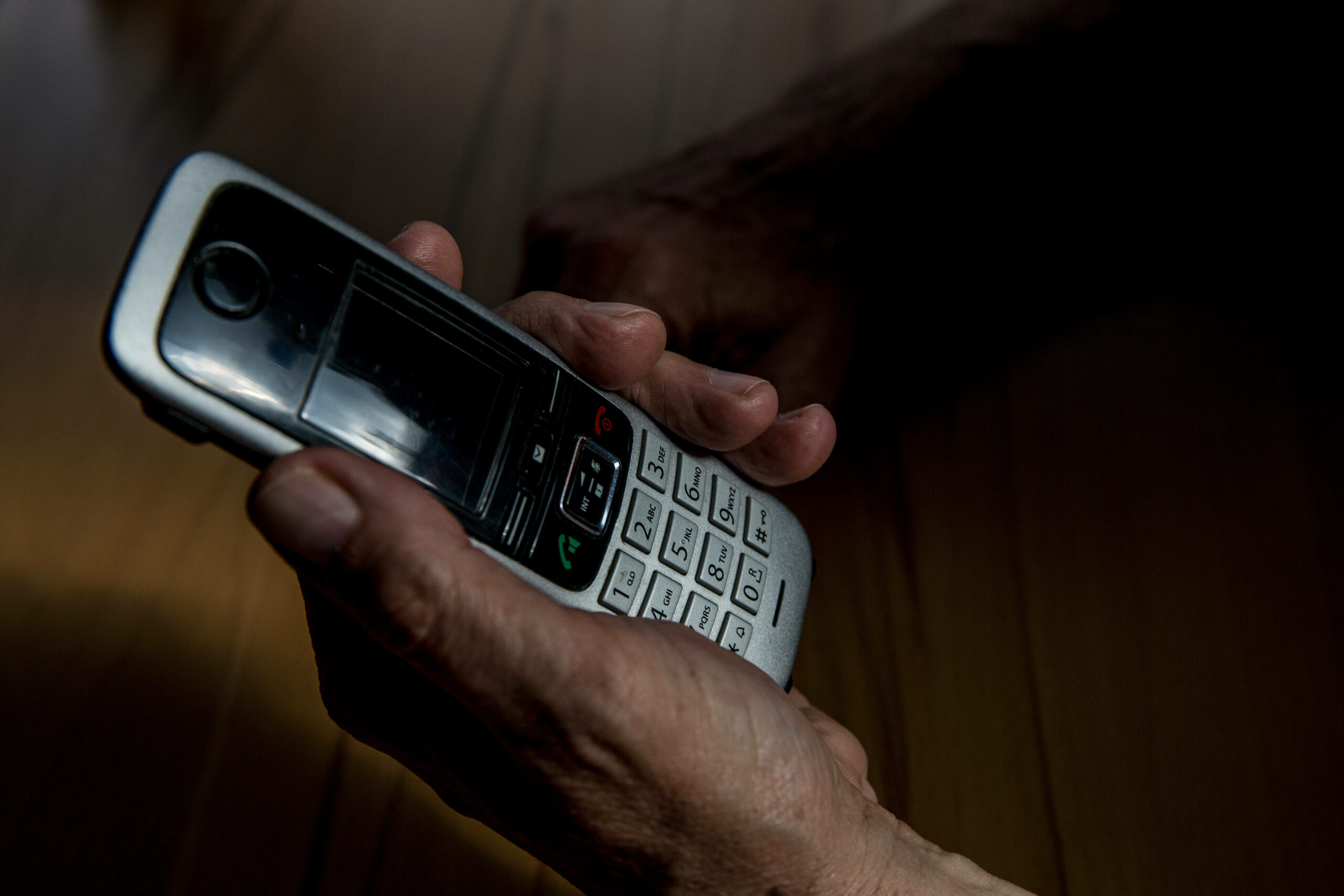 Die Hand eines älteren Menschen hält ein Telefon