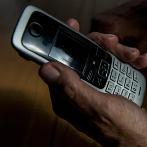 Die Hand eines älteren Menschen hält ein Telefon
