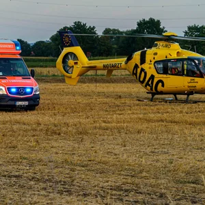 Rettungswagen und Rettungshubschrauber stehen auf einem Feld.