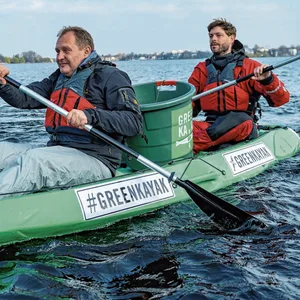Ein Kayak zum Müllsammeln, in dem zwei paddelnde Männer sitzen.