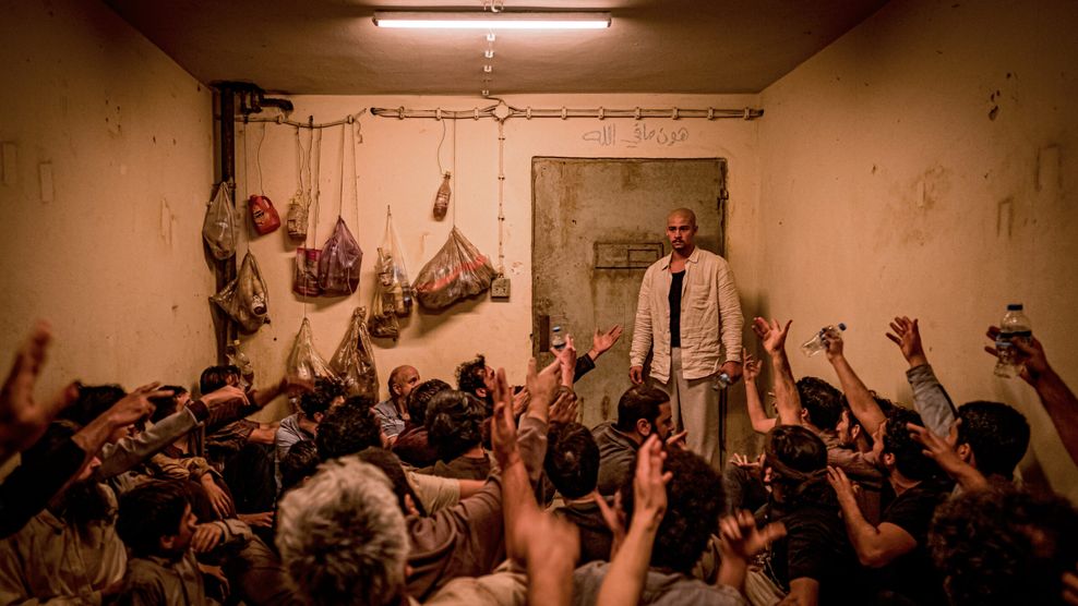Hajabi in einer engen Gefängniszelle, auf dem Boden vor ihm sitzen viele weitere Gefangene