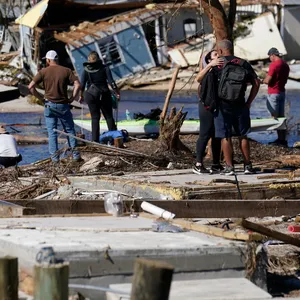 Menschen stehen auf der zerstörten Brücke nach Pine Island und betrachten die Schäden nach dem Hurrikan.