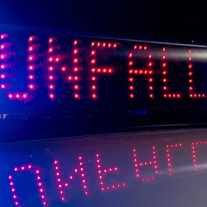 Das Blaulicht auf einem Fahrzeug der Polizei leuchtet in der Dunkelheit, während auf dem Display der Hinweis "Unfall" zu lesen ist