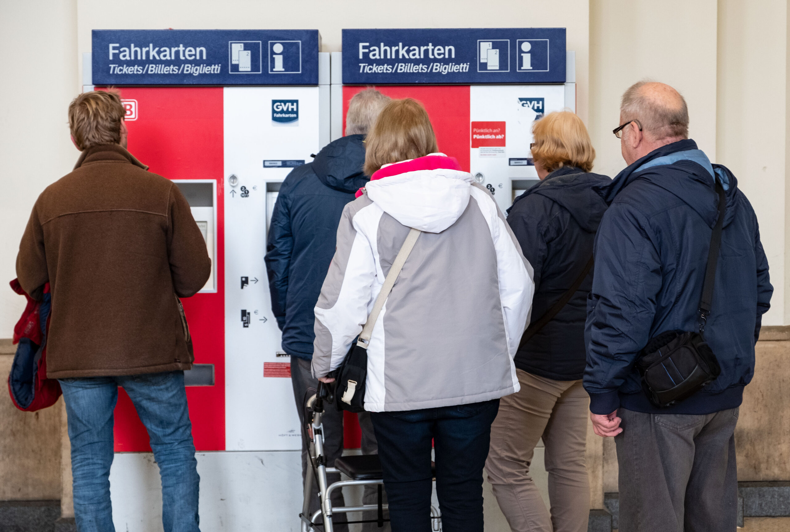 Fahrgäste stehen vor einem Fahrkartenautomat.