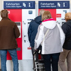 Fahrgäste stehen vor einem Fahrkartenautomat.