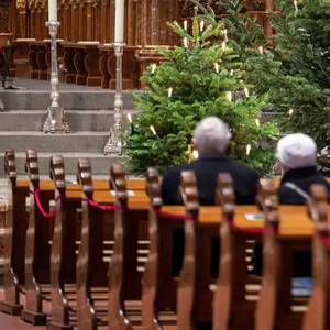 Menschen sitzen bei einem Weihnachtsgottesdienst in der Kirche