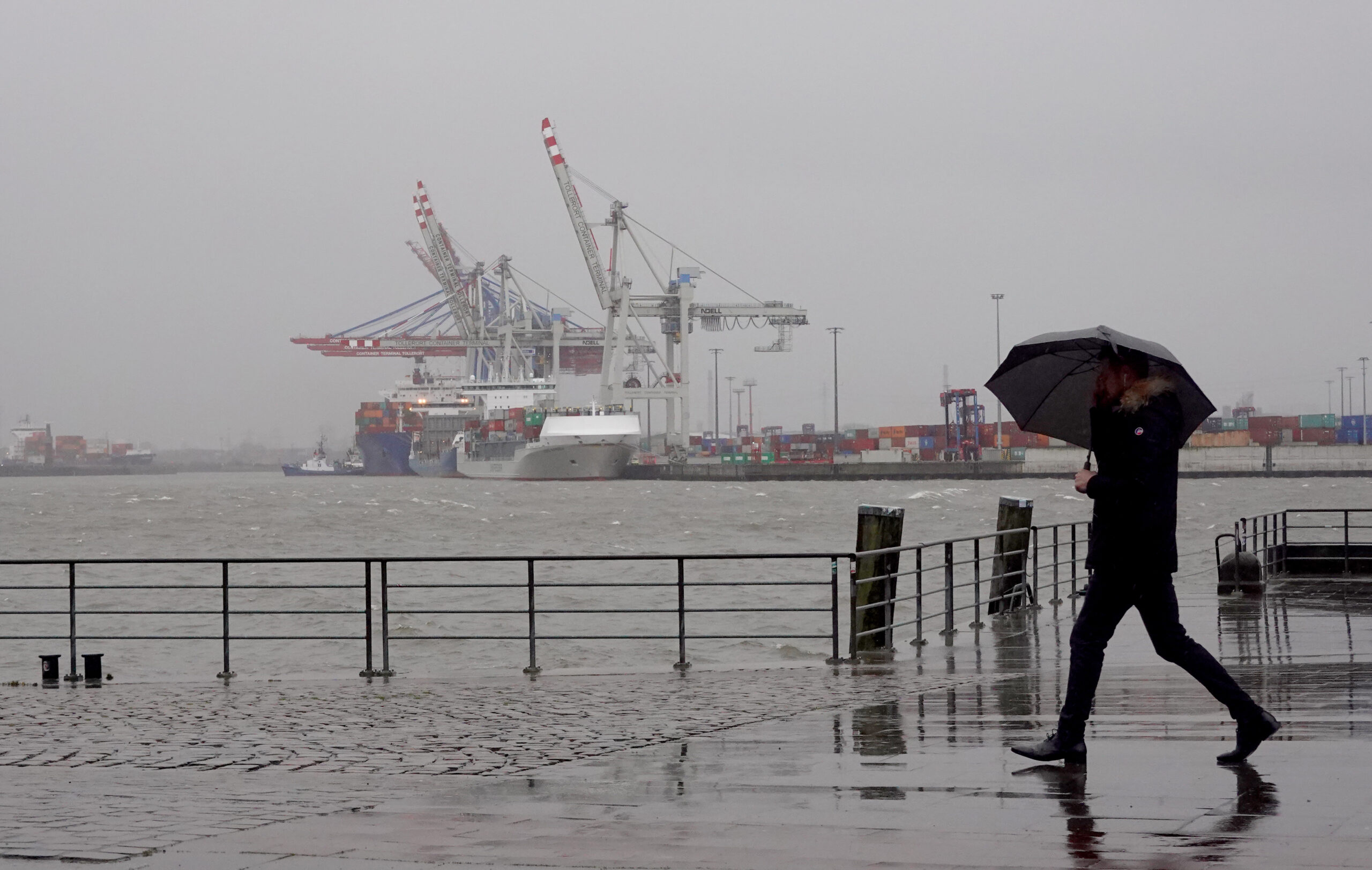 Ein Passant geht bei Regen und Wind an der Elbe entlang. (Archivbild)