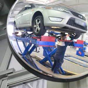 Ein TÜV- Prüfer prüft ein Fahrzeug, das auf einer Hebebühne steht.