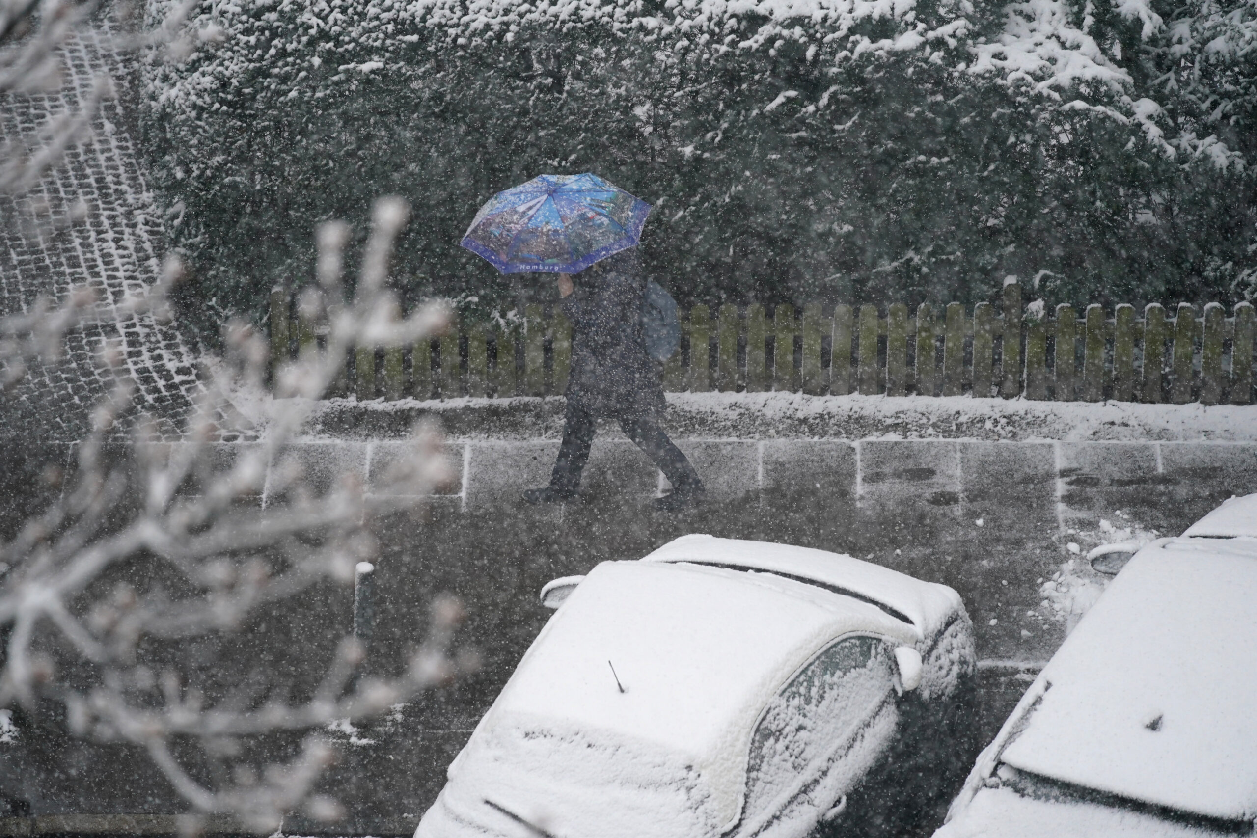 Mit einem Regenschirm läuft eine Passantin durch Schneeregen in Hamburg (Archivbild).