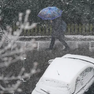 Mit einem Regenschirm läuft eine Passantin durch Schneeregen in Hamburg (Archivbild).