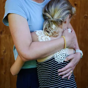 Ein Mädchen wird von einer erwachsenen Frau in den Arm genommen