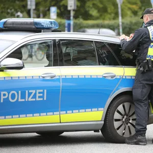 Zwei Hamburger Polizisten stehen vor einem Einsatzfahrzeug. (Symbolbild)