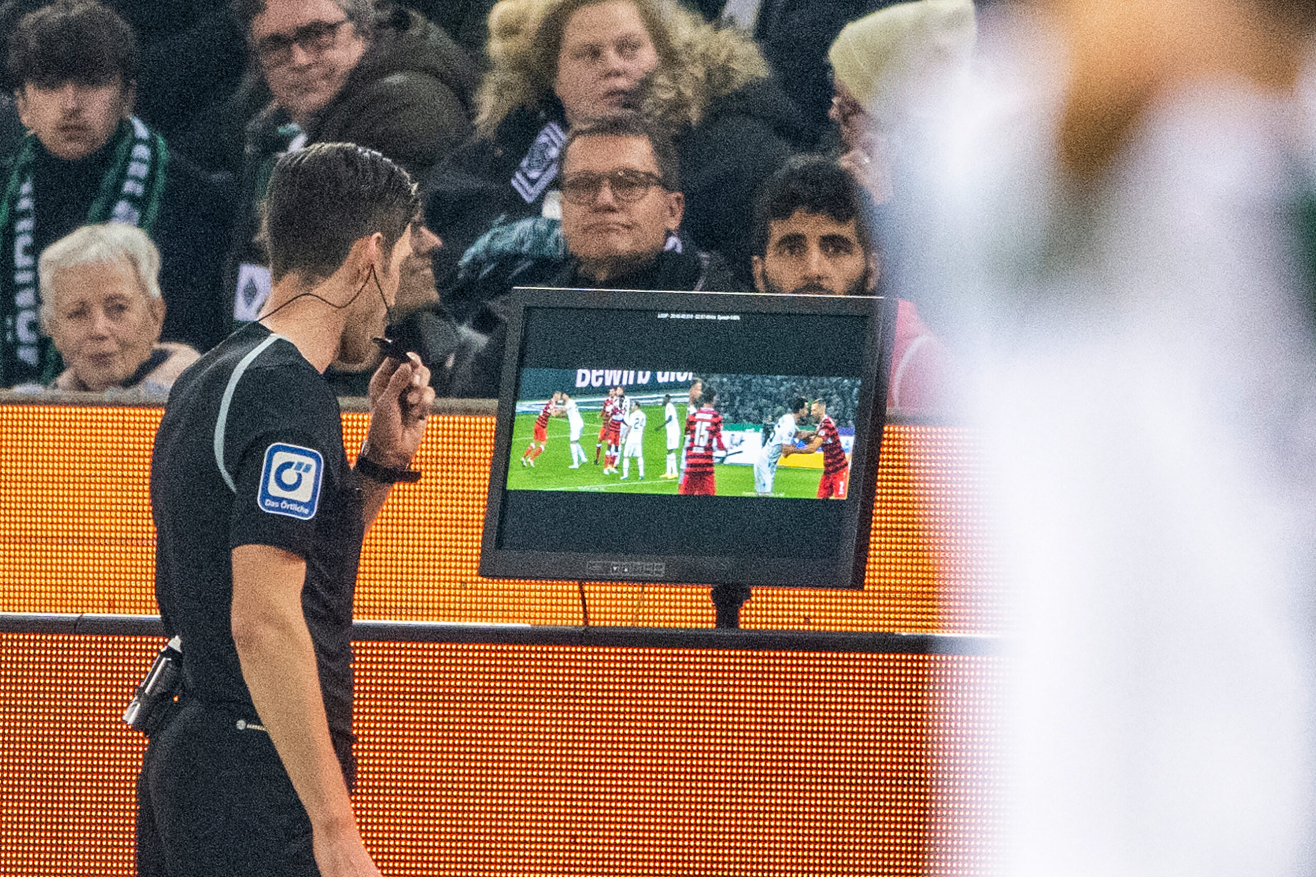 Schiedsrichter Matthias Jöllenbeck steht am VAR-Bildschirm und guckt sich die strittige Szene an.