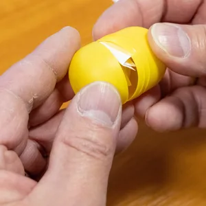 Ein Mann öffnet die gelbe Plastikverpackung eines Überraschungseis, mit dessen Hilfe in Altenpleen der Bürgermeister gelost wurde.