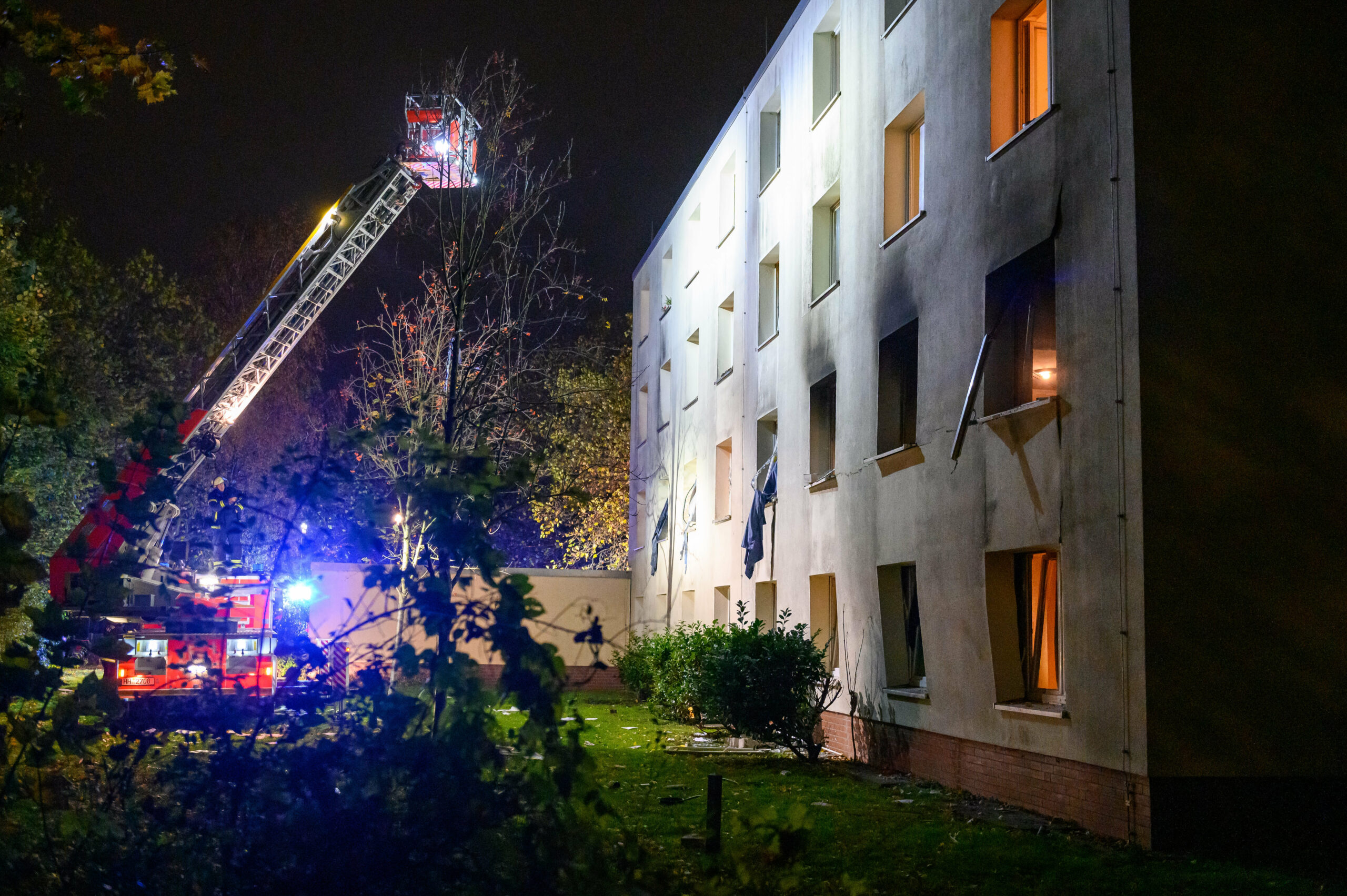 Eine Drehleiter der Feuerwehr beleuchtet die verrußte und beschädigte Fassade des Gebäudes in Stellingen, wo es eine Explosion gab
