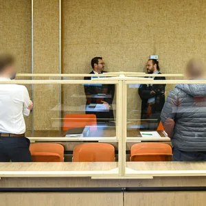 Zwei Angeklagte mit dem Rücken zum Fotografen. Vor ihnen: Ihre Verteidiger.