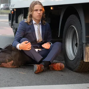 Ein Aktivist der Gruppe „Letzte Generation“ sitzt auf einer Kreuzung, während ein Lkw versucht, an ihm vorbeizukommen.
