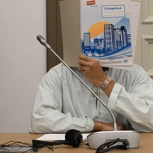 Ein Angeklagter versteckt sein Gesicht