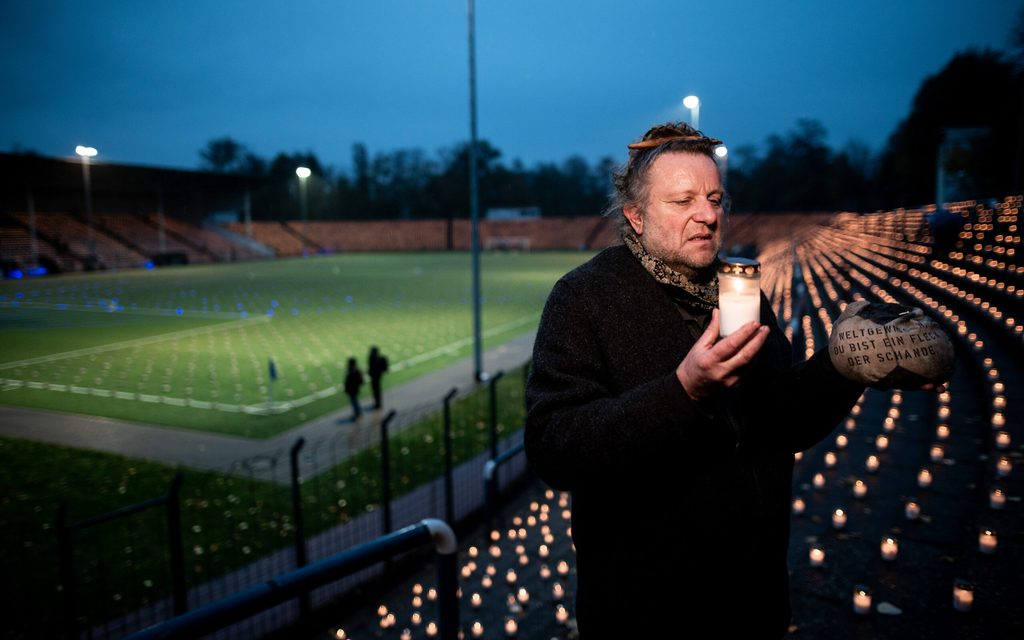 Der Künstler Volker-Johannes Trieb steht bei der Protestaktion auf dem Rasen des Stadions am Schloss Strünkede.