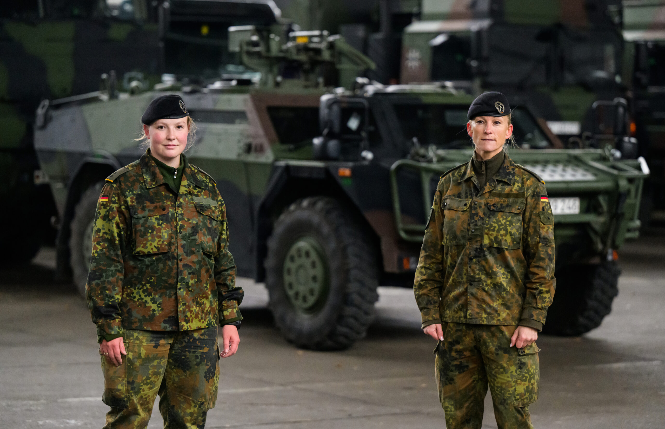Zwei Soldatinnen stehen vor einem Panzer.