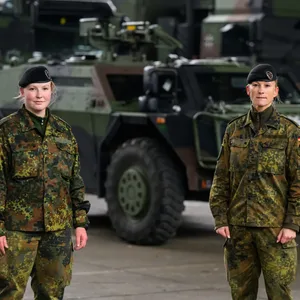 Zwei Soldatinnen stehen vor einem Panzer.