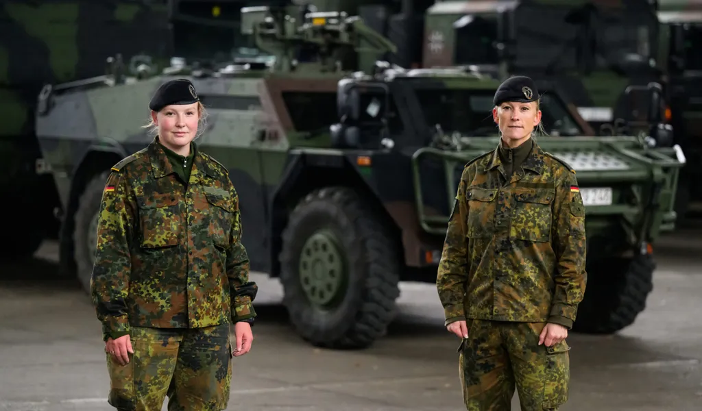 Zwei Soldatinnen stehen vor einem Panzer.