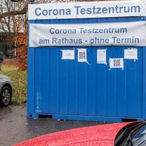 Ein in einem Container untergebrachtes Corona Testzentrum steht auf einem Parkplatz.