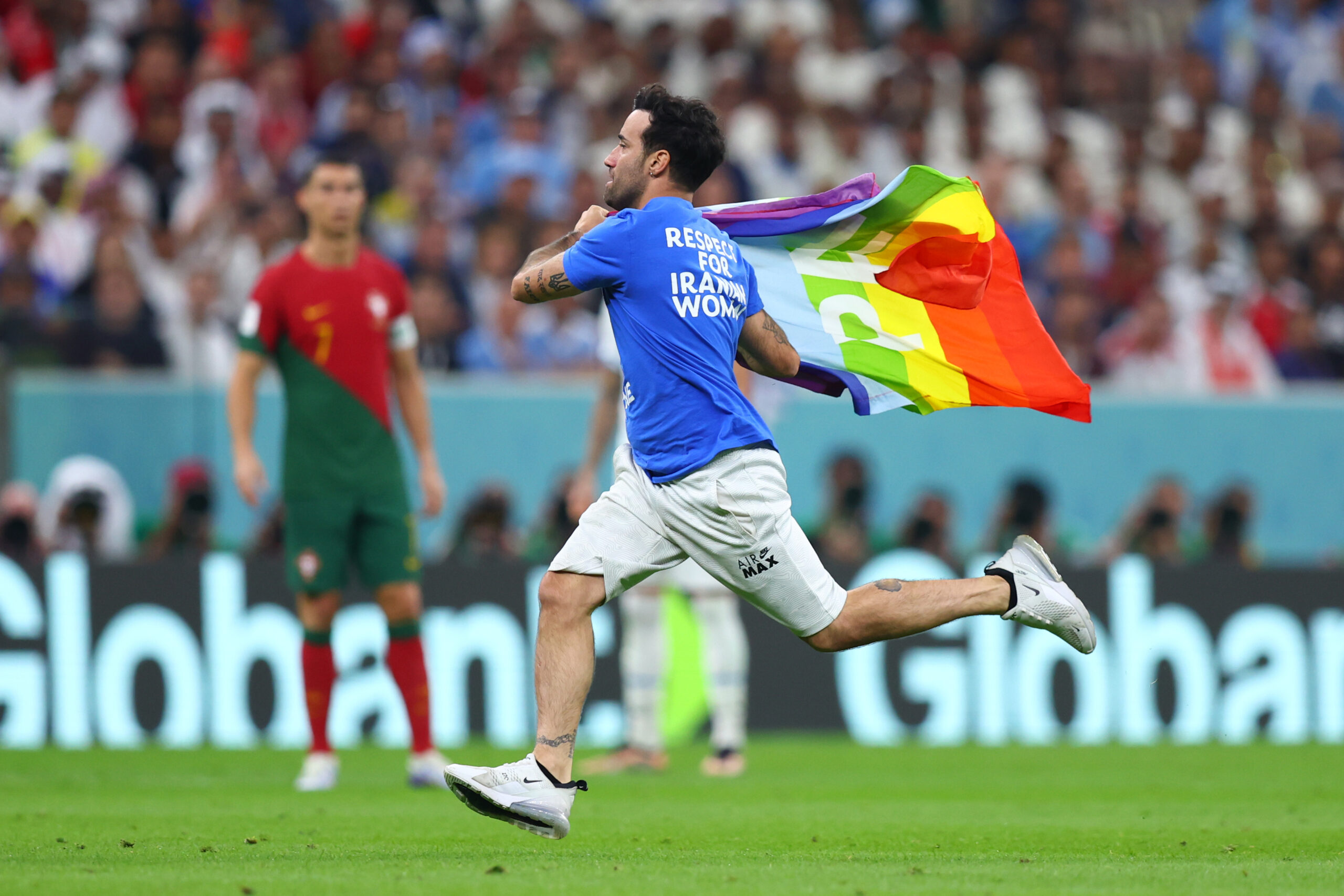 Ein Mann läuft mit T-Shirt und Regenbogen-Fahne über das Spielfeld.