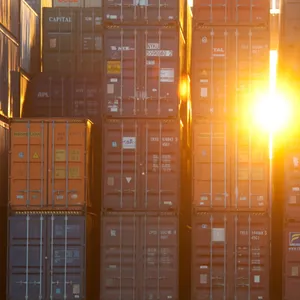 Die Sonne scheint zwischen Containern im Hamburger Hafen hervor