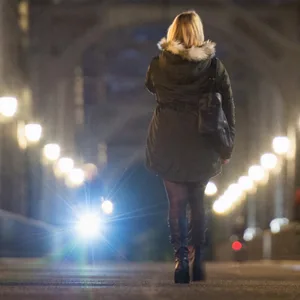 Eine Frau geht in Hamburg in der Dämmerung über die Alte Harburger Elbbrücke.