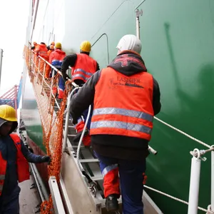Verladearbeiter (Lascher) gehen an Bord eines Containerschiffs