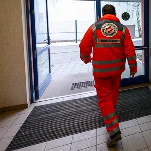 Ein Mitarbeiter vom Deutschen Roten Kreuz (DRK) geht durch den Eingang der künftigen Erstaufnahmeeinrichtung für Asylbewerber