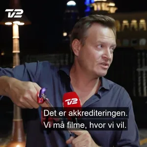 Der Dänische Journalist Rasmus Tantholdt zeigt Sicherheitskräften seine Akkreditierung.