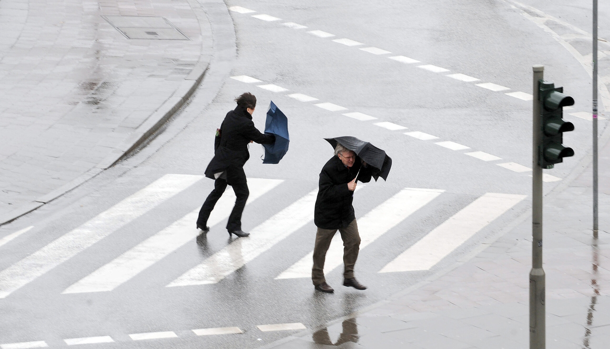 Fußgänger stemmen sich gegen eine Sturmböe (Symbolbild).