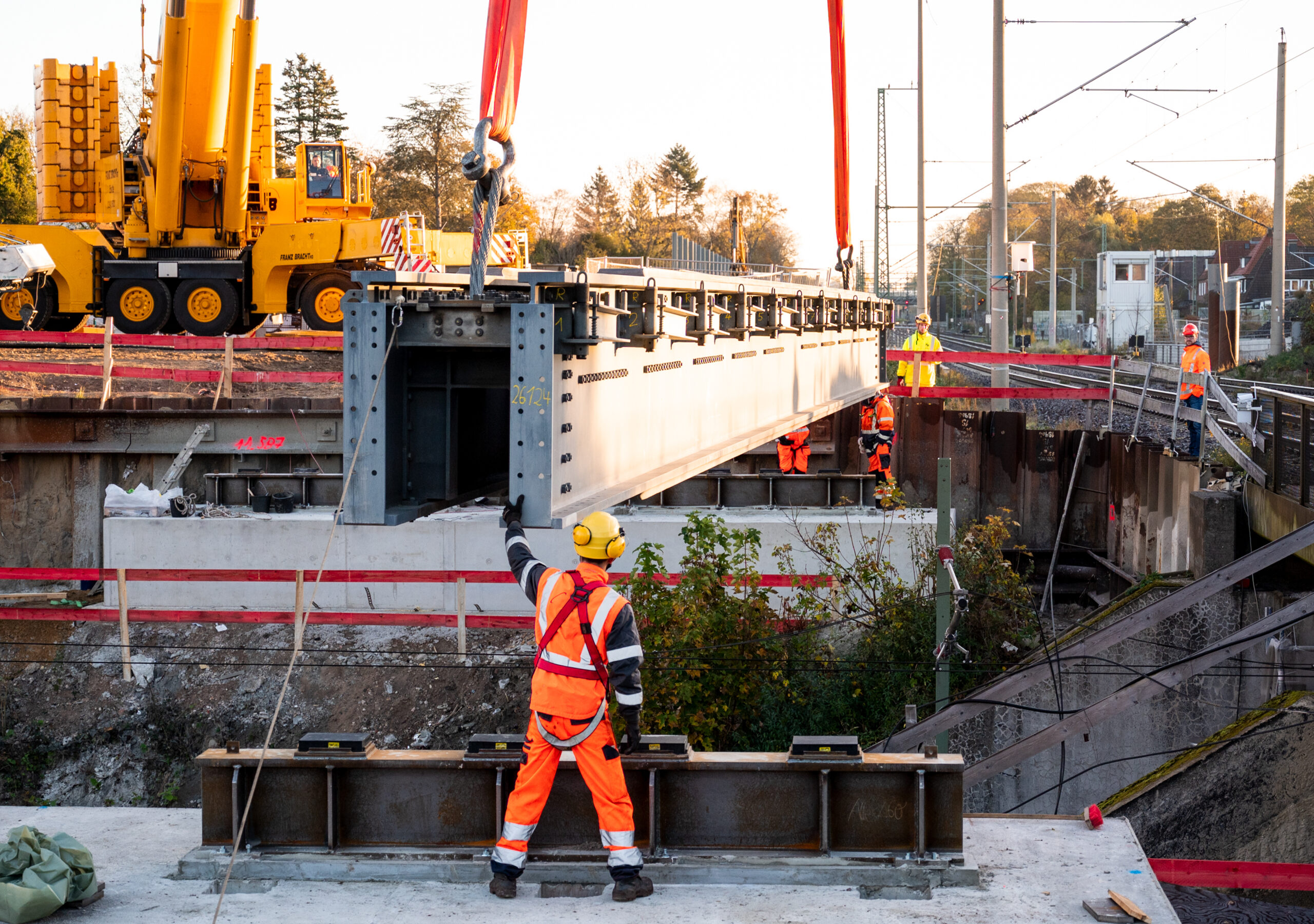 Teile einer Brücke werden auf der Baustelle der neuen S-Bahn-Linie S4 im Stadtteil Marienthal mit einem Kran eingehoben.