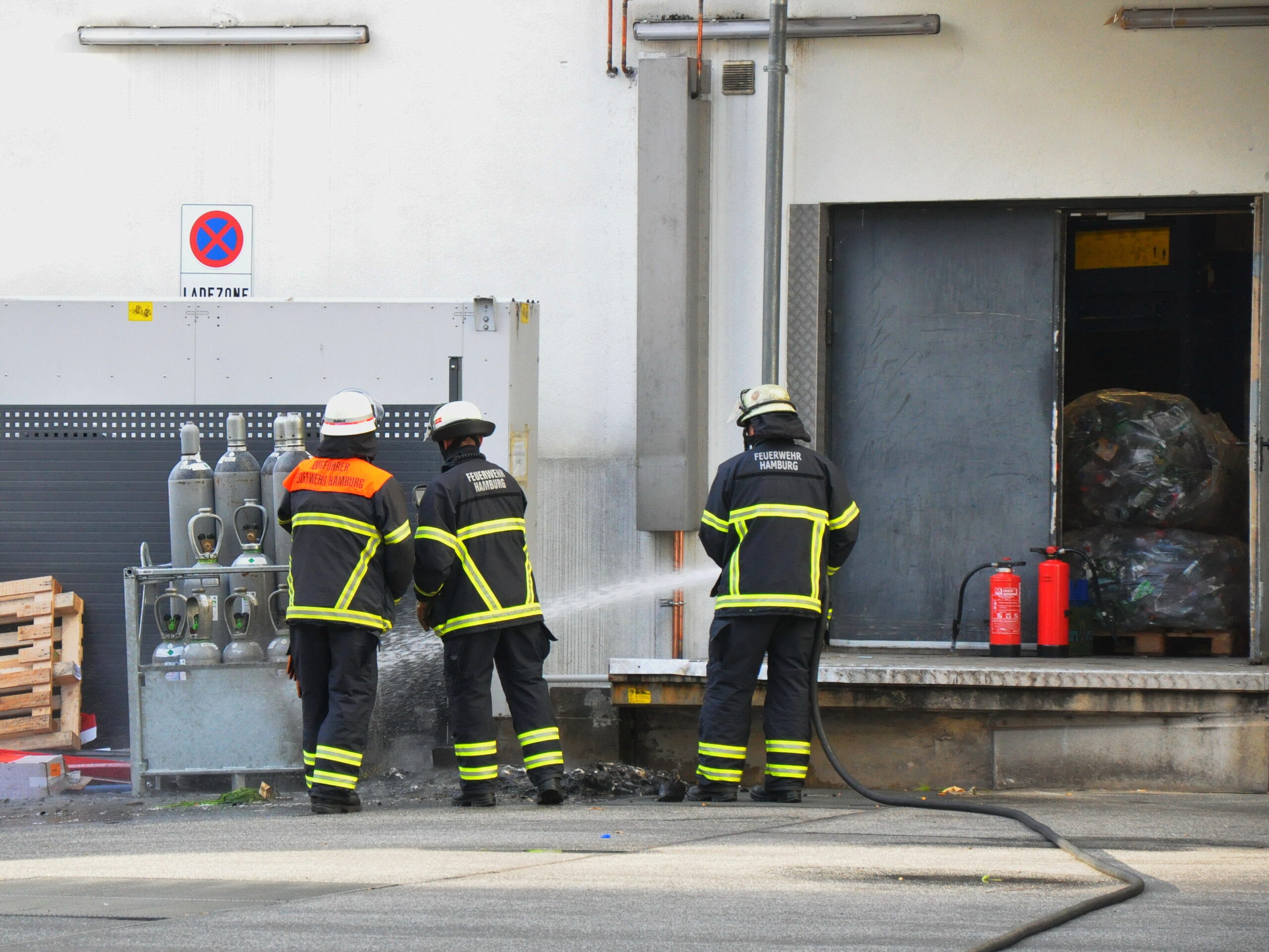Feuerwehrmänner kühlen Gasflaschen vor Aldi-Markt