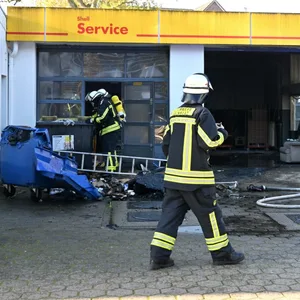 Feuerwehrmänner stehen auf dem Gelände einer Tankstelle in Buchholz, wo ein Feuer ausgebrochen war