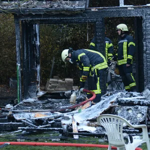 Feuerwehrleute vor der völlig ausgebrannten Gartenlaube.