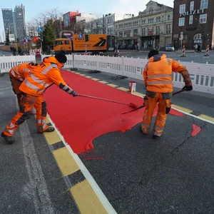 Straßenarbeiter färben den Radweg auf der Reeperbahn rot ein