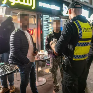Polizisten sprechen mit Männern vor einem Imbiss in St. Georg, wo eine Razzia stattfand