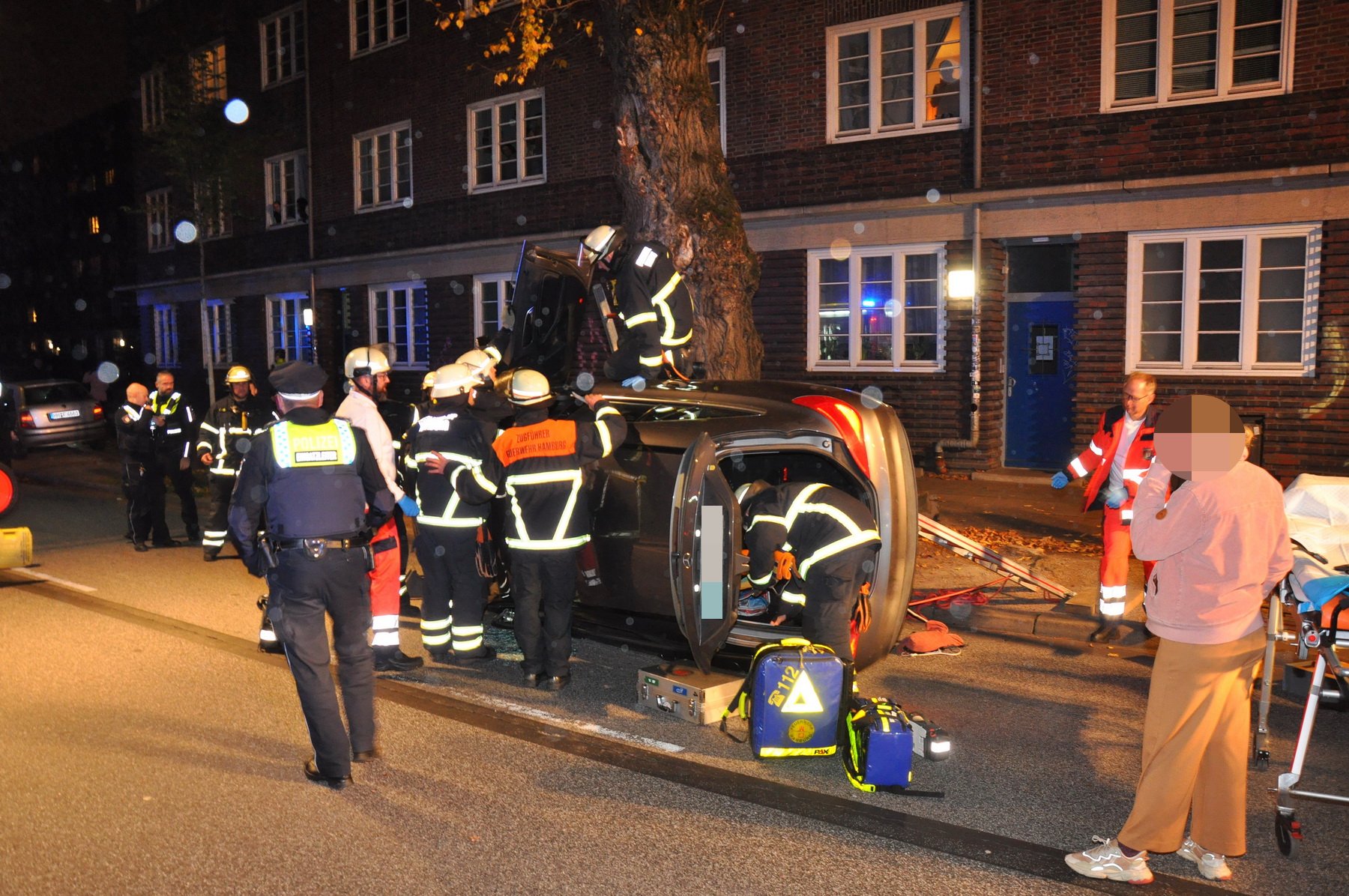 Rettungskräfte stehen um ein Auto in Eimsbüttel, das auf der Seite liegt