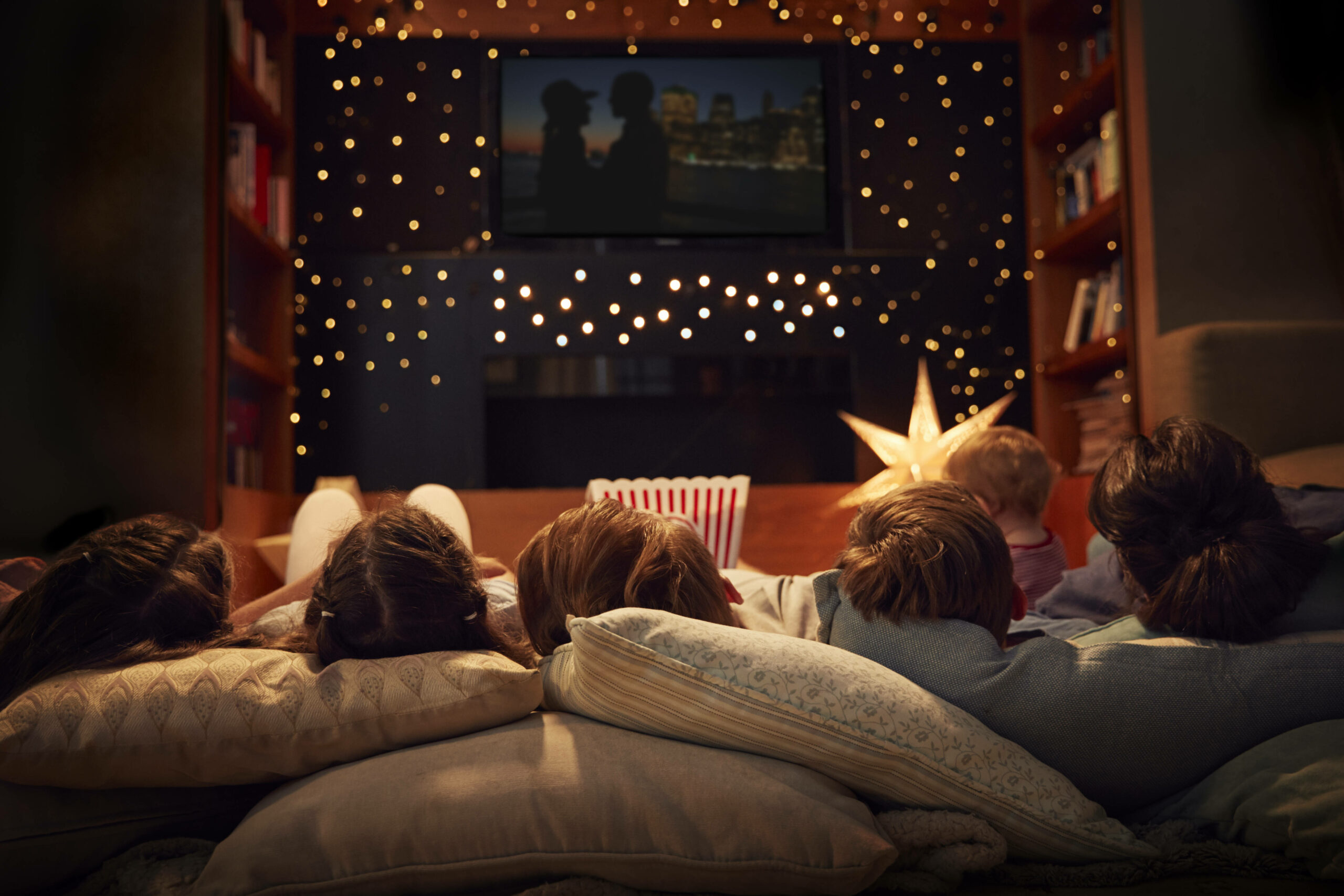 Eine Familie liegt auf einem Sofa und schaut einen Weihnachtsfilm