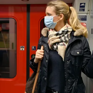 Eine Frau steht mit einer Schutzmaske in einer S-Bahn