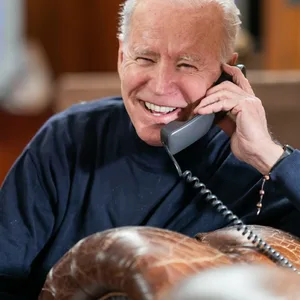Joe Biden lacht während eines Telefonats.